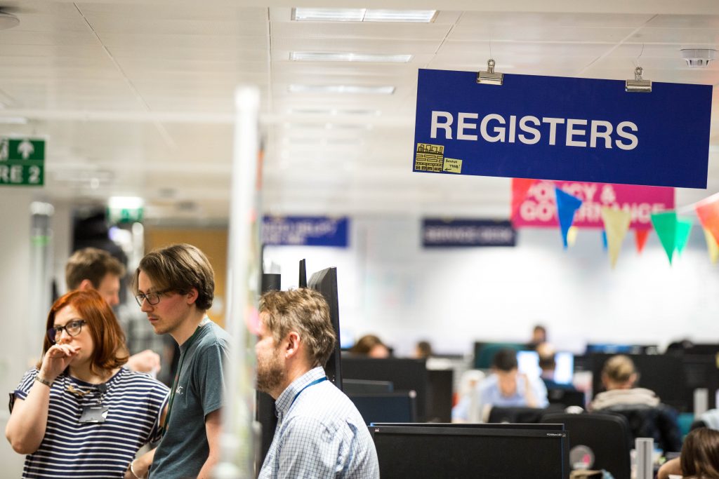 The Register team taking part in a standup and the Register sign